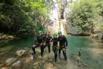 A small group on a canyoning adventure in Montenegro, wearing safety equipment and wetsuits.