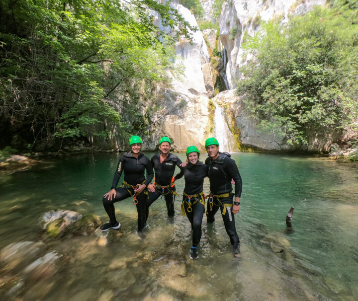 A small group on a canyoning adventure in Montenegro, wearing safety equipment and wetsuits.