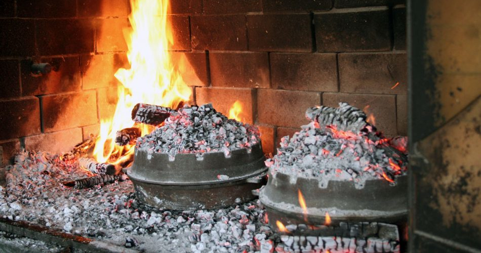Peka cooking in Croatia using pots covered in embers, placed close to the fire