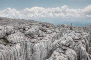 A hiker stands on a massive karst rock plateau on Maganik mountain in Montenegro