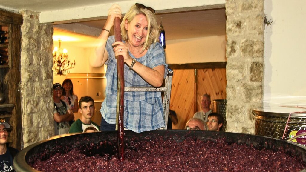 Guest has a go at stirring the grapes in a wine cellar in Montenegro