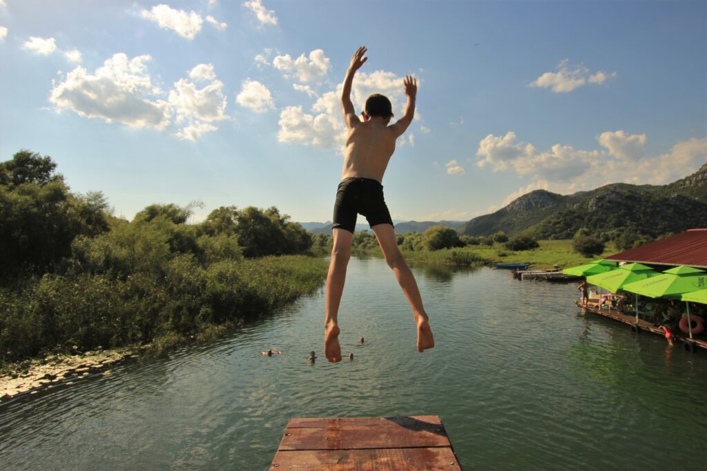 Family travel - young guest jumping into a river