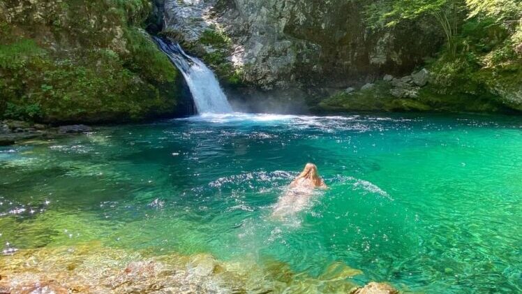 A woman wild swimming in the pristine but cold emerald waters of the Blue Eye at Theth National Park, Albania.