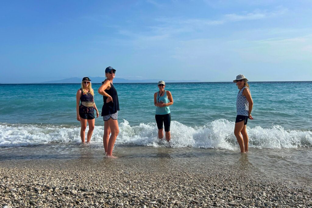 Four female travellers getting their feet wet in the Ionian Sea at Qeparo beach in Albania - too early in the year to go swimming.