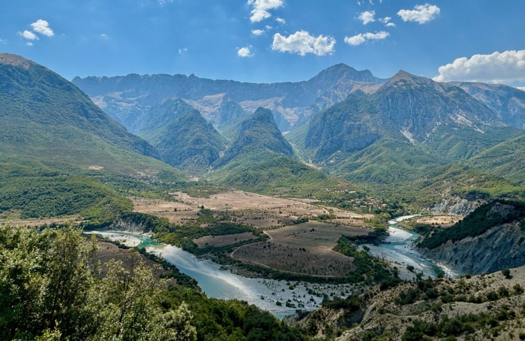 The Vjosa river winding through South Albania's verdant green mountains; it's low water levels in summer allowing safe wild swimming.