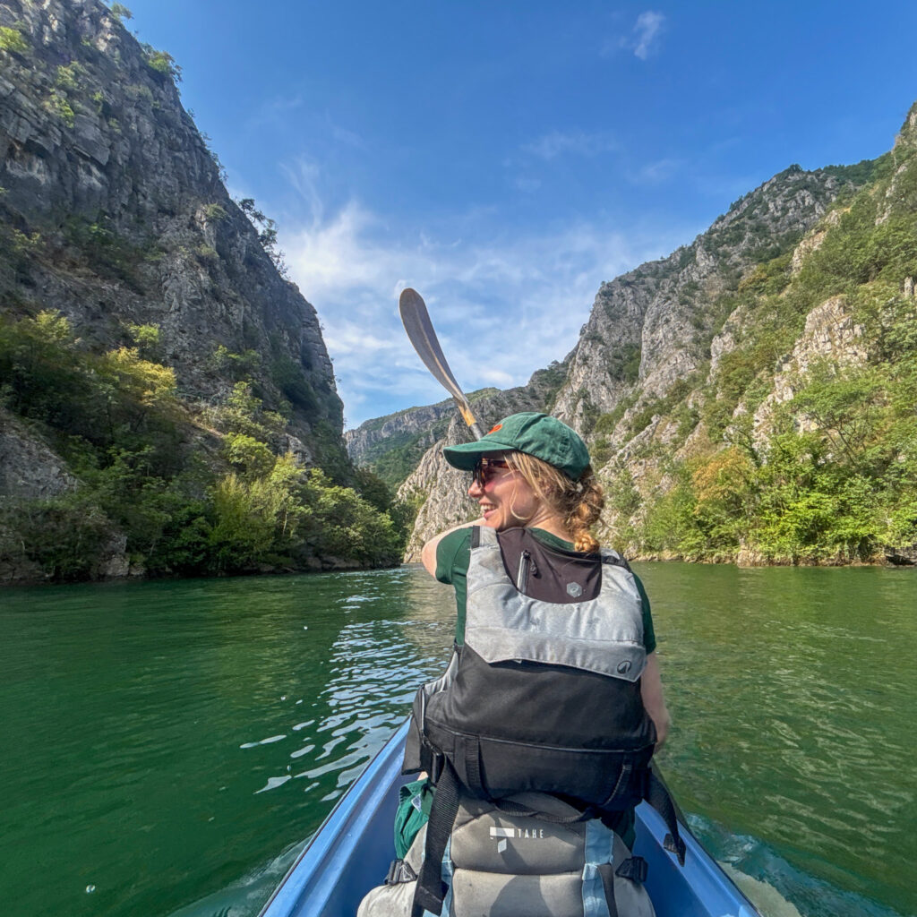 A woman with plaited hair and sun-hat, kayaking on the emerald waters of the Matka Canyon's Treska river in North Macedonia